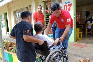 Red Cross volunteer assists person in wheelchair